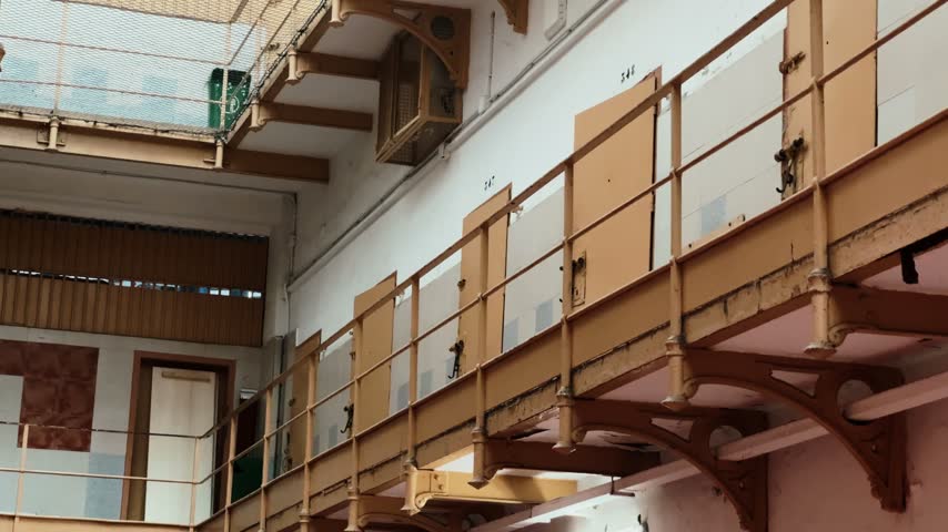 Close-up of old prison cell doors and metal balconies inside a historic jail building. Interior of abandoned detention facility, correctional institution and criminal justice concept.