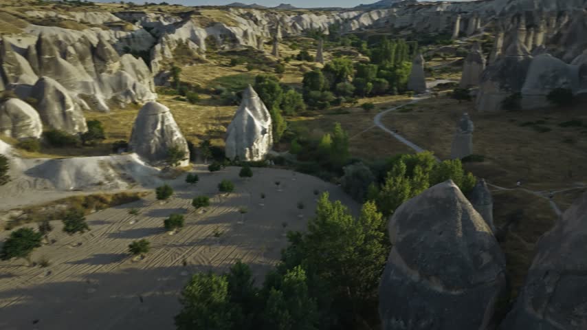As the sun sets over Love Valley in Cappadocia, the landscape is bathed in a warm, golden light. The unique rock formations stand quietly under the expansive sky.