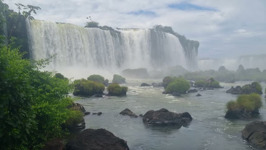 Panoramic view of Iguazú Falls from the Brazilian side, with immense volumes of water cascading over the rocky cliffs and plunging into the basin below at this iconic natural landmark