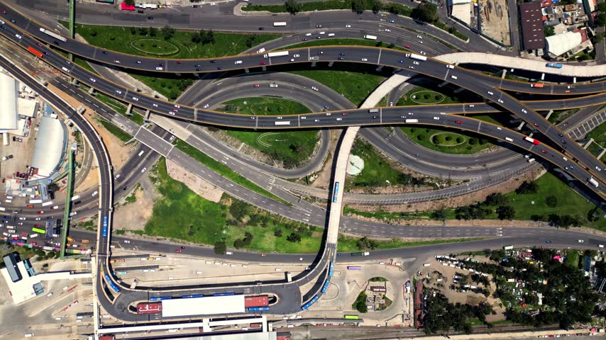Impressive top down aerial view of a busy, complex multi level highway interchange with cars, trucks, and public transport flowing through the intricate network of roads in Mexico City