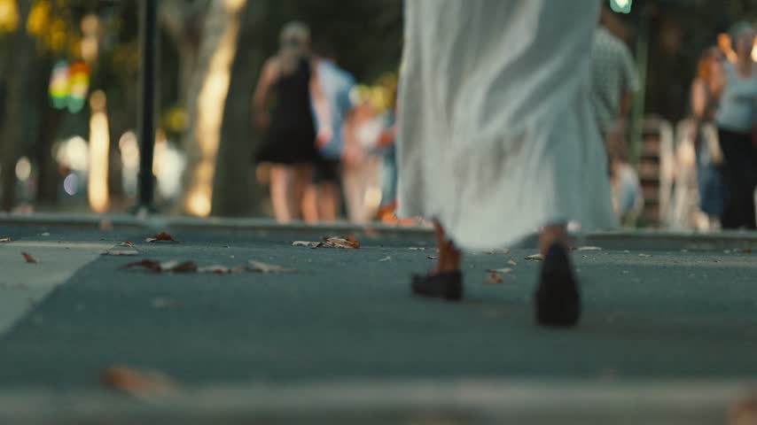 Person in white dress walking in slow motion on city street