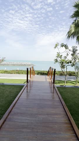 A scenic wooden walkway extending toward the turquoise sea,.