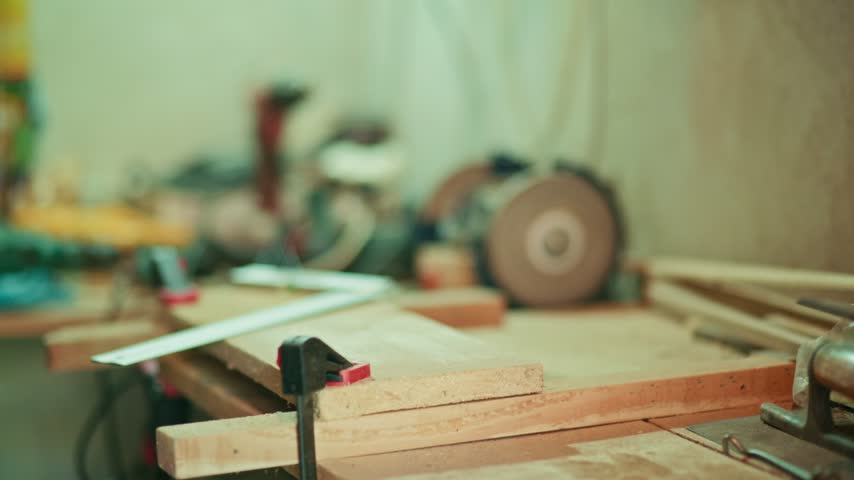 Close-up of a craftsman using a red pencil and metal square to mark drilling points on a wooden plank in a workshop. Authentic DIY woodworking footage for craft and maker projects