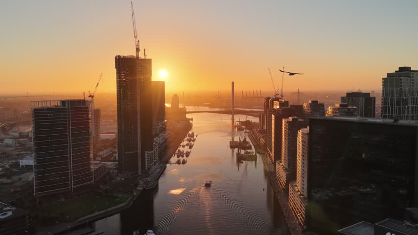 Port Melbourne, Victoria, Australia – 4K aerial drone view of Bolte Bridge over Yarra River, CBD skylines, Port of Melbourne container terminal, industrial waterfront at golden sunset