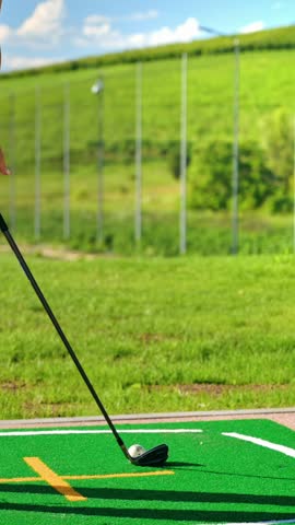 Close up slow motion footage golfer hitting ball with iron club at outdoor driving range sunny day professional training.