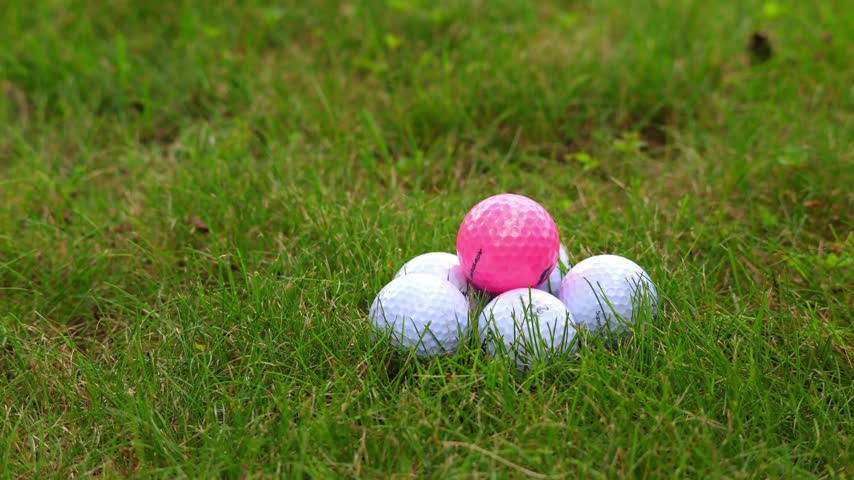 A hand places a golf ball on the golf course. Slow motion.