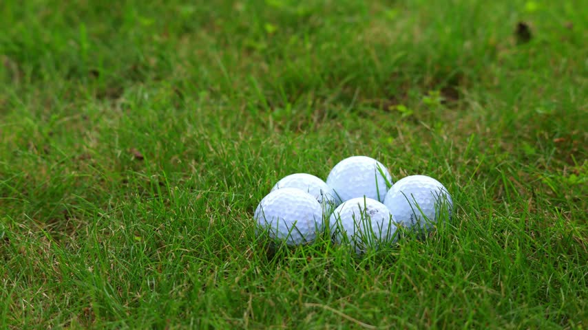 A hand places a golf ball on the golf course. Slow motion.