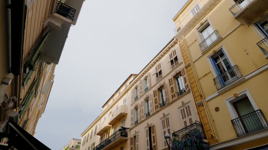 Looking up at classic French Riviera buildings along a narrow street in Cannes