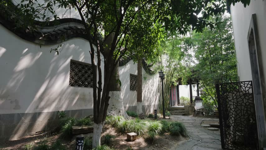 Nanjing, China - September 25th 2026 - Photo of irregular stone paved path leading through a traditional courtyard between whitewashed walls and lattice windows.
