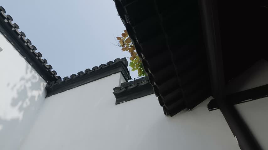 Nanjing, China - September 25th 2026 - Photo of whitewashed residential wall with a small square wooden lattice window under grey tile eaves.