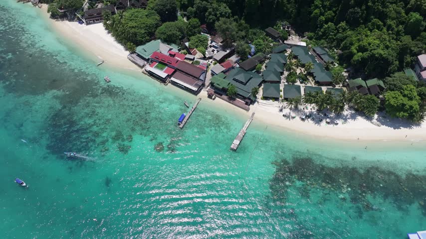 Aerial view of Perhentian Islands resort with white sand beach, wooden jetties, and turquoise water in Terengganu, Malaysia.