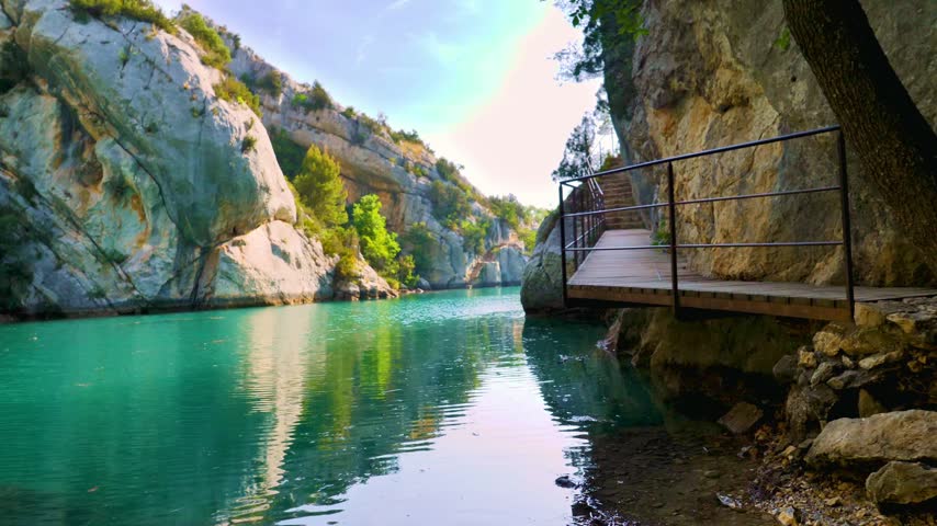 wooden walkway along turquoise river canyon with rocky cliffs in verdon gorge france
