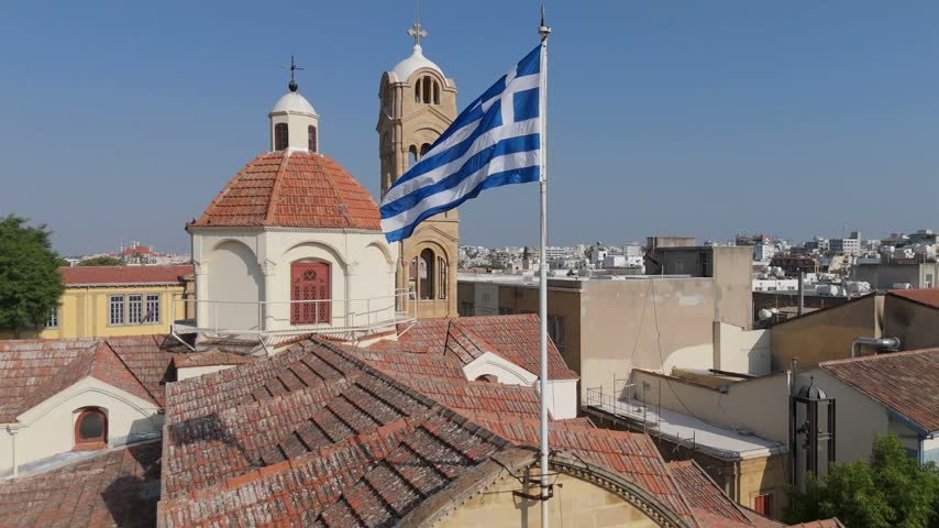Aerial view of a historic church with a terracotta tiled roof and a waving Greek flag in the old town of Nicosia, Nicosia, Cyprus.