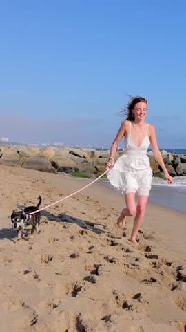 Attractive woman walking on the beach with her dog. Slow Motion.Vertical video.
