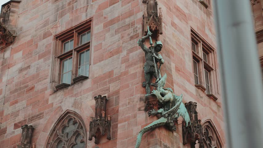 Cinematic push in shot of the St. George copper statue slaying a Dragon at the facade wall of the historic Rathaus St. Johann (City Hall) in Saarbrücken, Saarland, Germany as one of many details