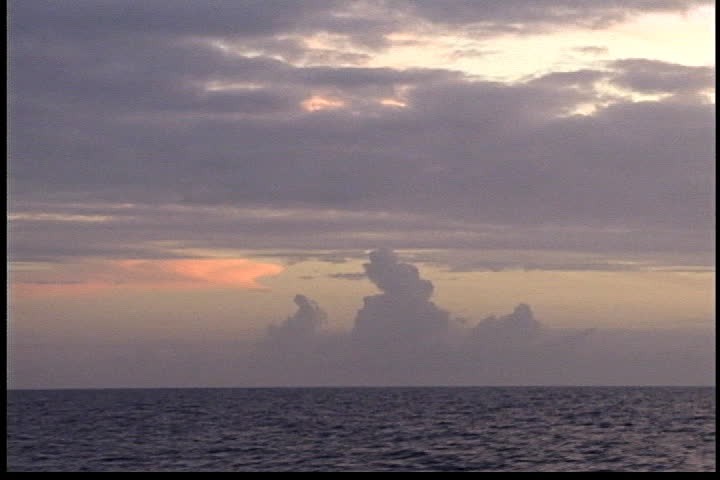 Sun shines through dark purple and pink clouds above Atlantic Ocean.