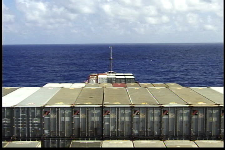 Rows of cargo containers stacked at back of cargo ship moving on Atlantic Ocean.