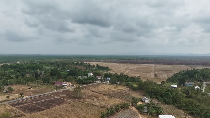 Aerial View of Rural Agricultural Landscape with Farmland and Village Under Cloudy Sky