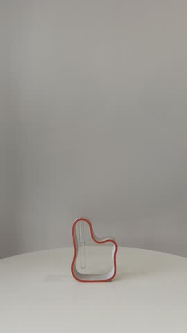Person placing and replacing different fresh flowers in a modern handmade designer vase on a white table