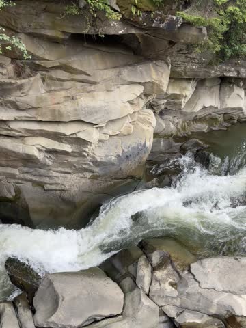 Scenic mountain river waterfall cascading through steep rocky sandstone canyon walls