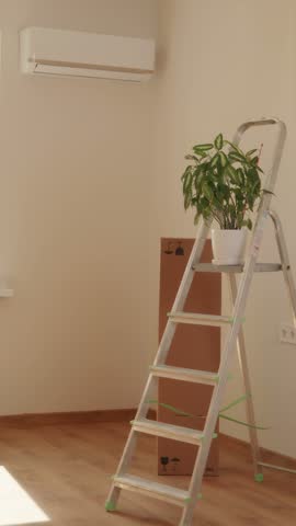 Homeowner or painter holding paint roller looking at white renovated wall surface inside bright room.