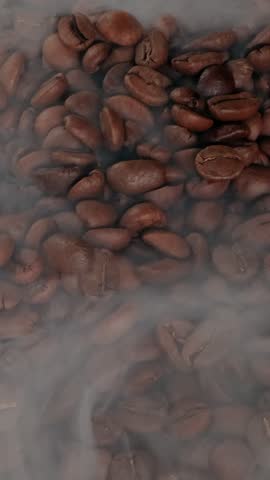 Close up of seeds of coffee. Fragrant coffee beans are roasted smoke comes from coffee beans.
