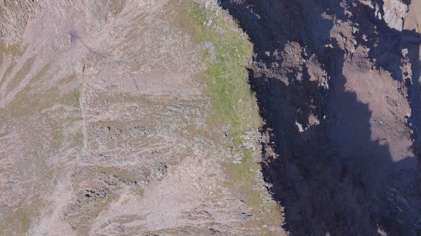 Downward aerial view of sunlit rock formations and deep shadows in Tyrol, Austria
