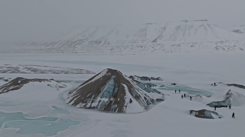 Aerial view of a glacier mound surrounded by snow and meltwater pools in the arctic landscape of Pyramiden, Svalbard, Svalbard and Jan Mayen.
