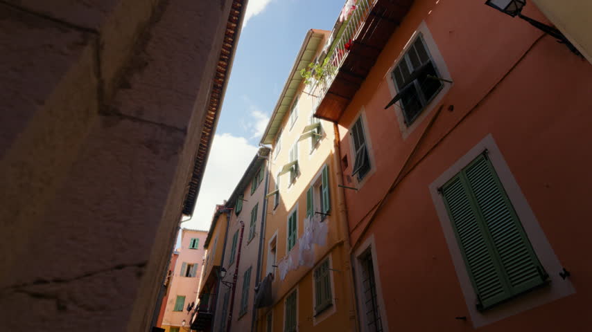 Colorful old buildings with shutters and laundry line along a narrow sunlit street