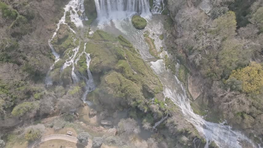 Aerial view of the cascading Marmore Falls surrounded by lush green vegetation and rocky cliffs in Terni, Umbria, Italy.