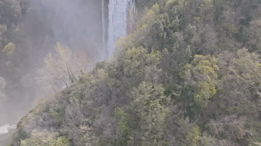 Aerial view of the cascading waters of Marmore Falls surrounded by lush forest vegetation in Terni, Umbria, Italy.