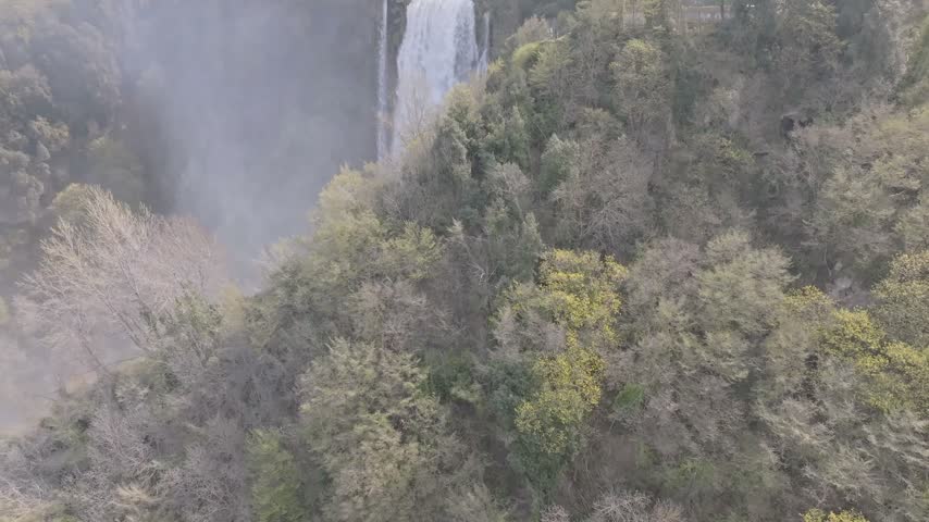 Aerial view of Marmore Falls cascading through lush green forests in the Umbria region of Terni, Umbria, Italy.