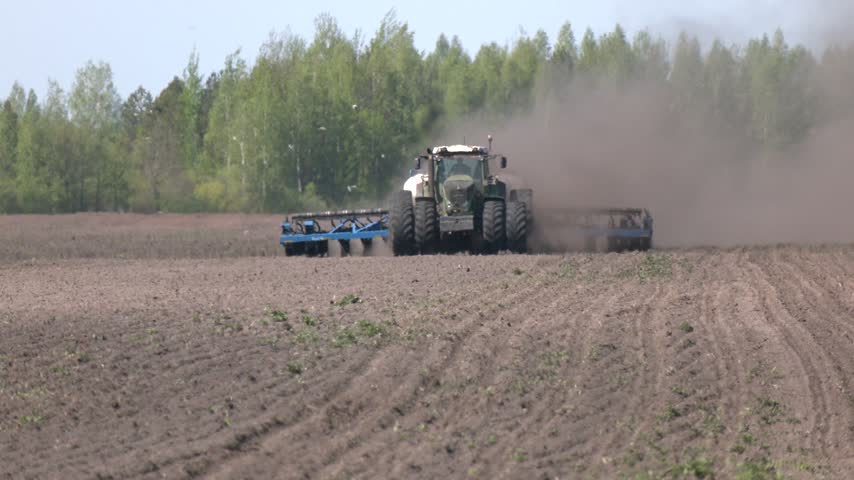 The tractor is used to sow seeds in the field using a specialized device. The tractor is a powerful tool for agricultural work. Tractor working in the field. Time of sowing. 