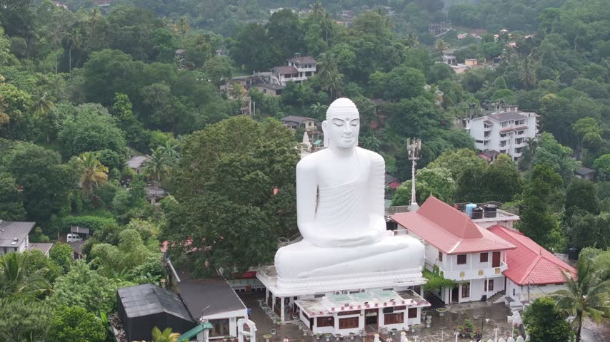 Aerial view of the large white Bahirawakanda Vihara Buddha statue overlooking the lush green hills and urban landscape of Kandy, Central Province, Sri Lanka.