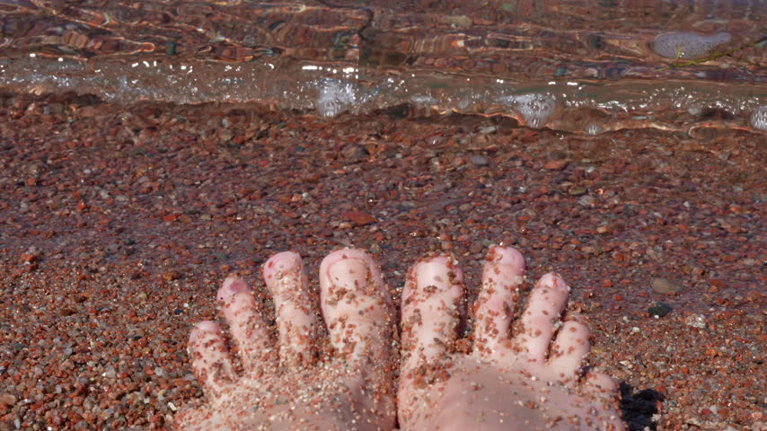 4K POV footage of bare feet in sand wiggling toes on lake shore with gentle waves washing up, Lake Issyk Kul Kyrgyzstan