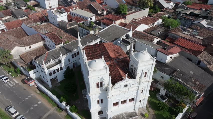 Aerial view of the iconic Jami Ul-Alfar Mosque with its distinctive red and white striped architecture surrounded by dense urban rooftops in Colombo, Western Province, Sri Lanka.
