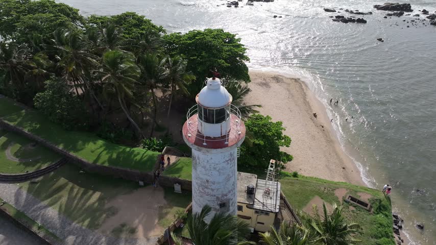 Aerial view of the historic Colombo Lighthouse surrounded by palm trees and coastal greenery overlooking the Indian Ocean in Colombo, Western Province, Sri Lanka.