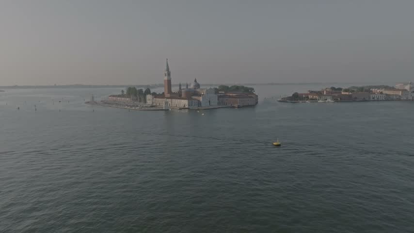 Aerial view of San Giorgio Maggiore island with its iconic bell tower and church surrounded by the calm waters of the Venetian lagoon in Venice, Veneto, Italy.