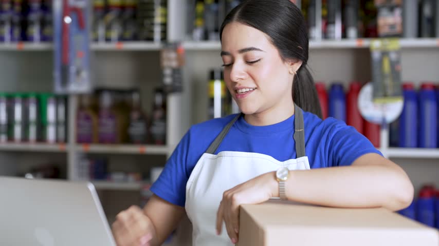 Young latina woman using a laptop for inventory and shipping management at an auto parts store
