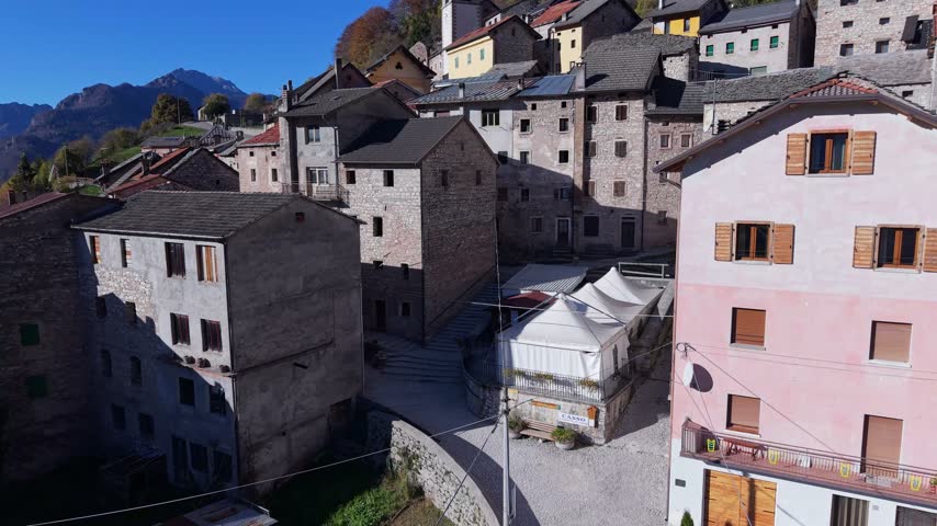 Aerial view of traditional stone houses and a small village square with white tents in Pordenone, Friuli-Venezia Giulia, Italy.