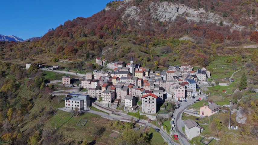 Aerial view of a historic mountain village with stone houses and a church tower nestled in the landscape of Pordenone, Friuli-Venezia Giulia, Italy.