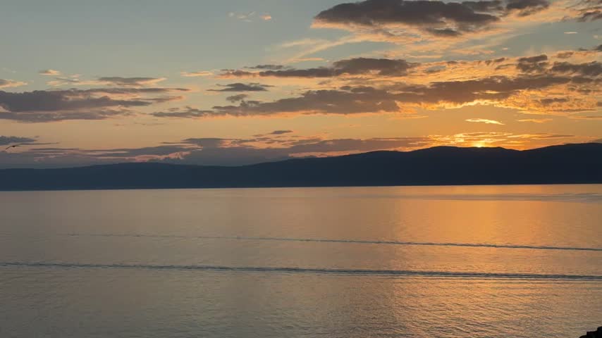 Time-lapse video of beautiful landscape of Baikal Lake at sunset. View from Olkhon Island coast to golden water of Small Sea in evening. Seagulls flying over the water. Natureal background