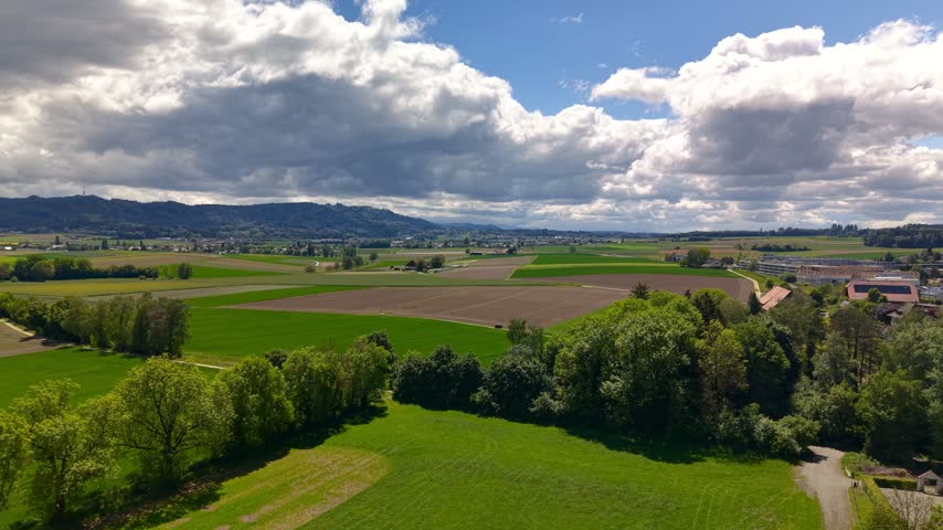 Moving clouds casting shadows over patchwork fields and meadows in a vast agricultural countryside