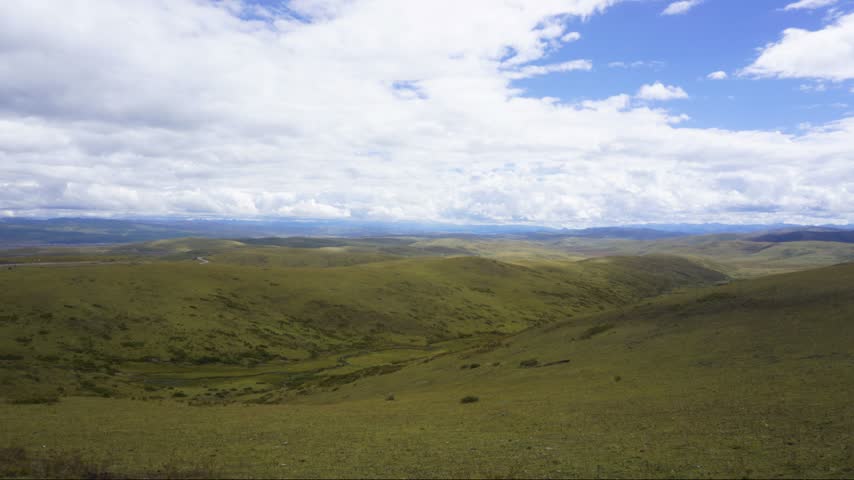 Time lapse shooting of vast plateau meadow,continuous gentle hills spread to the distance,large area of clouds cover the sky and slowly flow and disperse