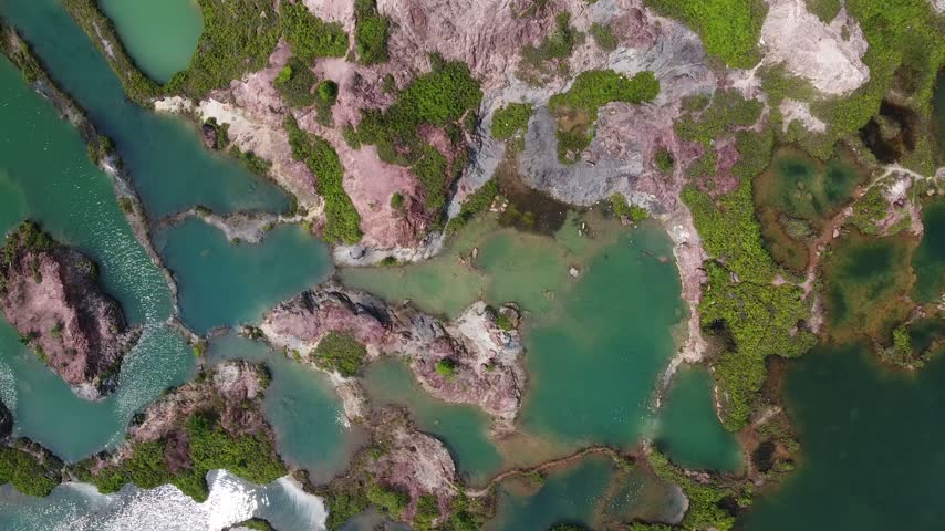 Aerial travel footage showing a remarkable turquoise lake landscape with rocky formations and green vegetation.