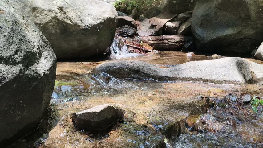 Natural water stream flowing between rocks outdoors