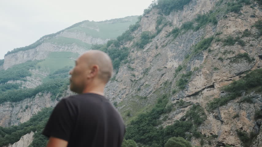 Man Traveler Looking At Majestic Steep Mountain Cliffs Contemplating Nature
