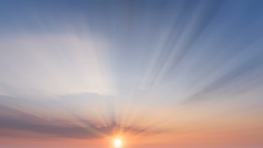 Wide angle view of a vibrant horizon where the sun glows behind soft clouds.