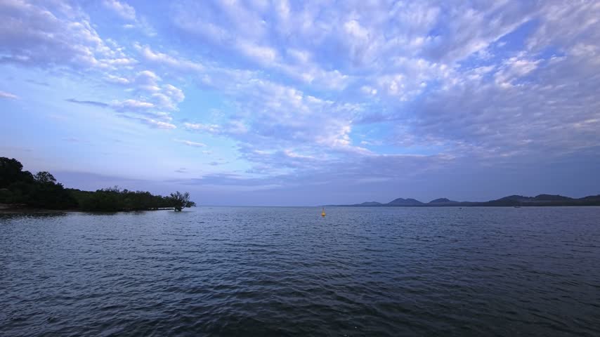 Tropical sunrise reaches a sandy beach with palm trees, white sand and clear water beside the tropical sea. Later, tropical sunset and golden hour extend across the island beach, beachfront and coastline while dusk, twilight and evening light follow the shoreline and island coast. Thailand, Southeast Asia.