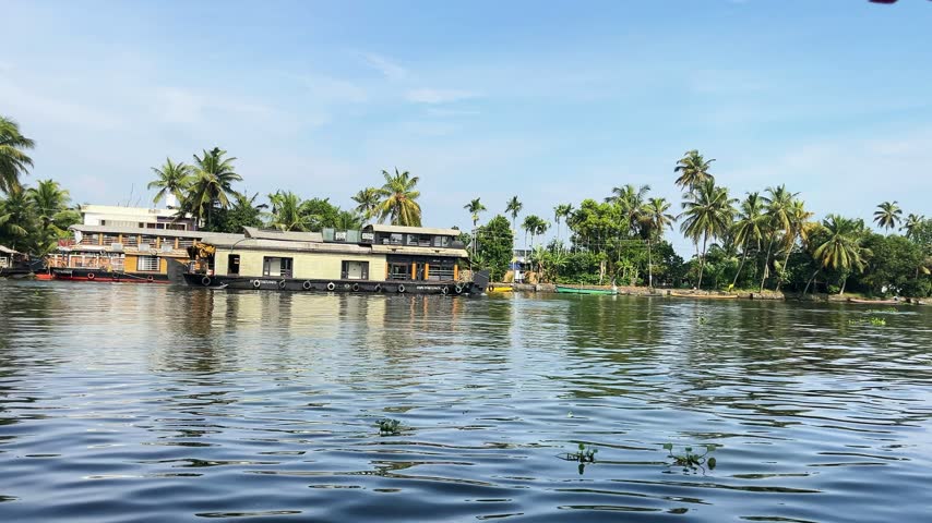  Traditional Kerala Houseboats Moored Along Palm Lined Riverside in Alleppey Backwaters. Low Angle View Across Rippling Backwater Lake Towards Moored Floating Houseboats.